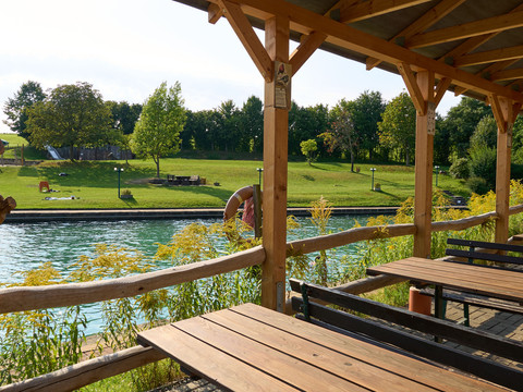 Holzterrasse mit Blick auf das Bad mit Bäumen.