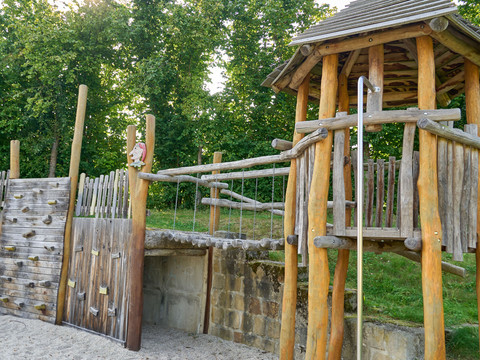 Holzspielplatz mit Klettergerüst und Rutsche.