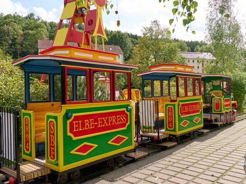 Elbefreizeitland Bunter Kinderzug "Elbe-Express" steht auf Schienen in einer ländlichen Umgebung.