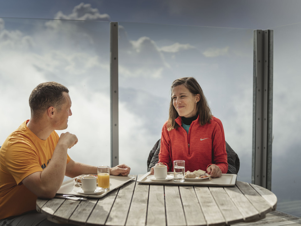 Petit déjeuner au-dessus de la mer de nuages Sonnenaufgangsfahrt Eggishorn mit Paar beim Frühstück auf der Terrasse über dem Wolkenmeer in der Aletsch ArenaSunrise trip Eggishorn with couple having breakfast on the terrace above the sea of clouds in the Aletsch ArenaExcursion au lever du soleil à l'Eggishorn avec un couple prenant son petit-déjeuner sur la terrasse au-dessus de la mer de nuages dans l'Aletsch Arena
