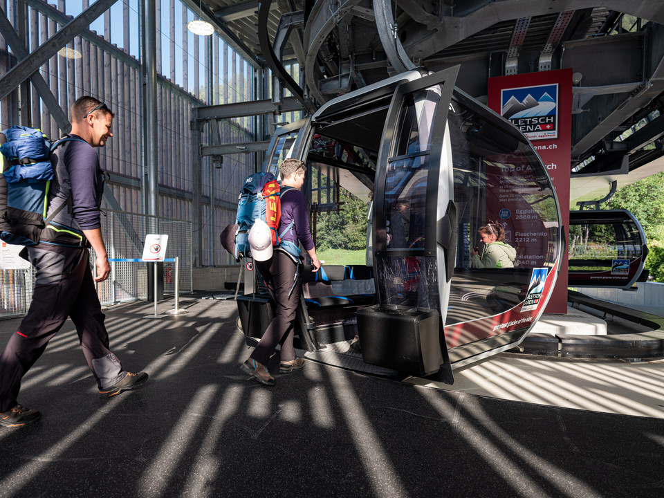 Komfortable Anreise mit der Gondel Aletsch Entdeckerpass mit Wanderern beim Einstieg in die Gondelbahn der Aletsch Bahnen in Fiesch