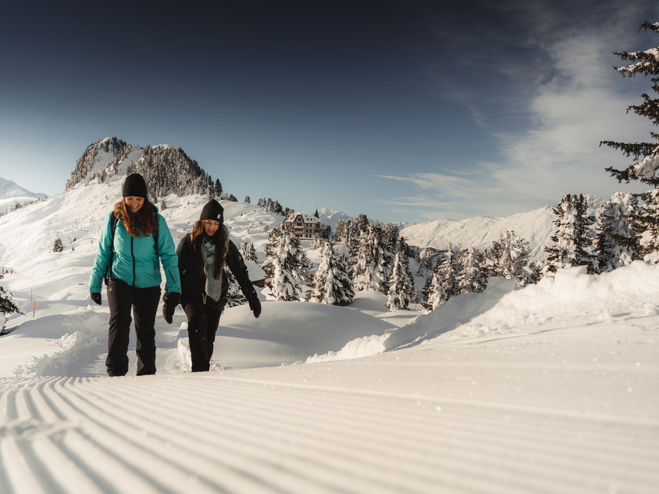 Winterwandern in der Aletsch Arena Aletsch Entdeckerpass mit zwei Frauen beim Winterwandern auf der Riederalp in der verschneiten Aletsch Arena
