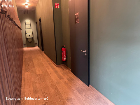 Toegang tot gehandicaptentoilet.jpg Brede hal met houten vloer en toegangsdeur naar het invalidentoilet