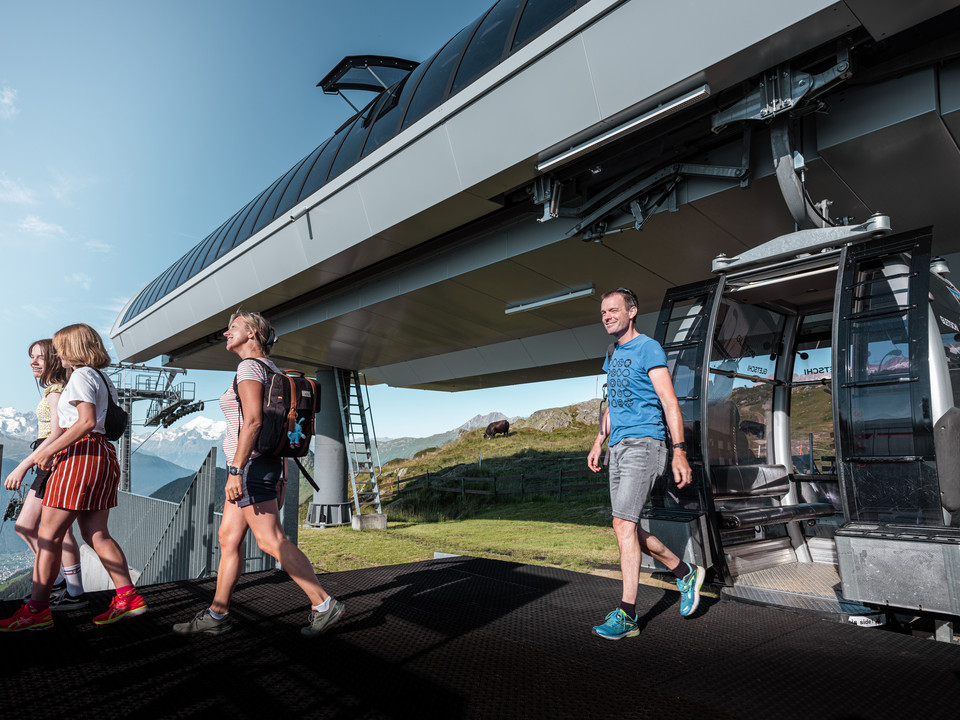 Arrivée dans le monde de la montagne Einzelfahrten Aletsch Arena mit Wanderern beim Ausstieg aus der Gondel an der Mittelstation auf der RiederalpSingle trips Aletsch Arena with hikers getting off the gondola at the middle station on the RiederalpCourses individuelles Aletsch Arena avec des randonneurs à la sortie de la télécabine à la station intermédiaire de Riederalp