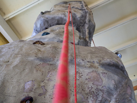 Indoor Hochseilgarten Kanuaktivtours Kletterwand aus Kunststoff mit roter Kletterseilführung in Innenraum.