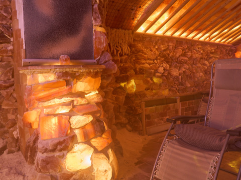 Salzgrotte Lindenhof Beleuchtete Salzsteine in der Salzgrotte mit Holzliegen und Decken.Illuminated salt stones in the salt grotto with wooden loungers and blankets.Osvětlené solné kameny v solné jeskyni s dřevěnými lehátky a dekami.Podświetlane kamienie solne w grocie solnej z drewnianymi leżakami i kocami.Verlichte zoutstenen in de zoutgrot met houten ligstoelen en dekens.Pietre di sale illuminate nella grotta di sale con lettini e coperte in legno.