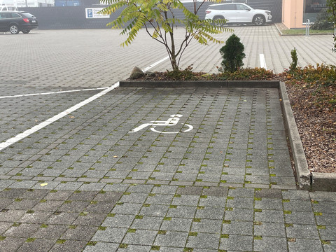 Behinderten-Parkplatz.jpg Parkplatz grau gepflastert mit RollstuhlfahrerzeichenGray paved parking lot with wheelchair accessible signsŠedé dlážděné parkoviště s označením bezbariérového přístupuGrijs geplaveide parkeerplaats met bordjes voor rolstoelgebruikersSzary utwardzony parking ze znakami dostępu dla wózków inwalidzkichParcheggio asfaltato grigio con segnaletica di accesso per sedie a rotelle