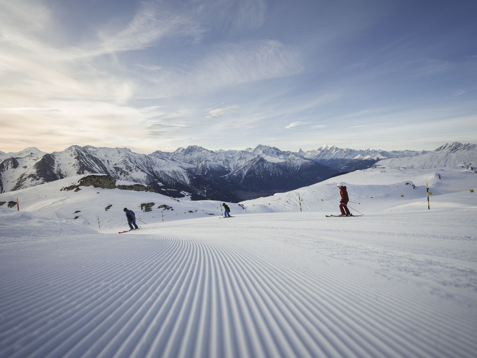 Skier avant tout le monde First Track Bettmerhorn mit Skifahrern auf frisch präparierter Piste mit Panoramablick auf die Walliser AlpenFirst Track Bettmerhorn with skiers on a freshly groomed piste with panoramic views of the Valais AlpsFirst Track Bettmerhorn avec des skieurs sur une piste fraîchement préparée offrant une vue panoramique sur les Alpes valaisannes