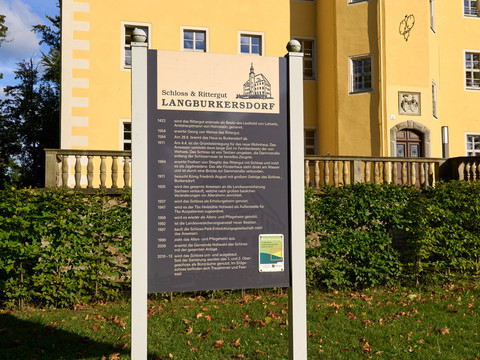 Kulturscheune und Schloss Langburkersdorf Informationsstele vor Schloss Langburkersdorf mit Text und Grafik.Information stele in front of Langburkersdorf Castle with text and graphics.Informační stéla před hradem Langburkersdorf s textem a grafikou.Stela informacyjna przed zamkiem Langburkersdorf z tekstem i grafiką.Informatiesteen voor het kasteel van Langburkersdorf met tekst en afbeeldingen.Stele informativa davanti al castello di Langburkersdorf con testo e grafica.