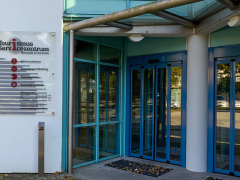 Tourismus Service Zentrum Neustadt (Sachsen) Eingangsbereich eines Gebäudes mit blauen Glastüren und einem Schild "Tourismus Servicezentrum".Entrance area of a building with blue glass doors and a sign "Tourism Service Center".Vstupní prostor budovy s modrými skleněnými dveřmi a nápisem "Centrum služeb pro cestovní ruch".Wejście do budynku z niebieskimi szklanymi drzwiami i napisem "Centrum Usług Turystycznych".Entree van een gebouw met blauwe glazen deuren en een bord "Tourism Service Centre".Ingresso di un edificio con porte in vetro blu e insegna "Centro servizi turistici".