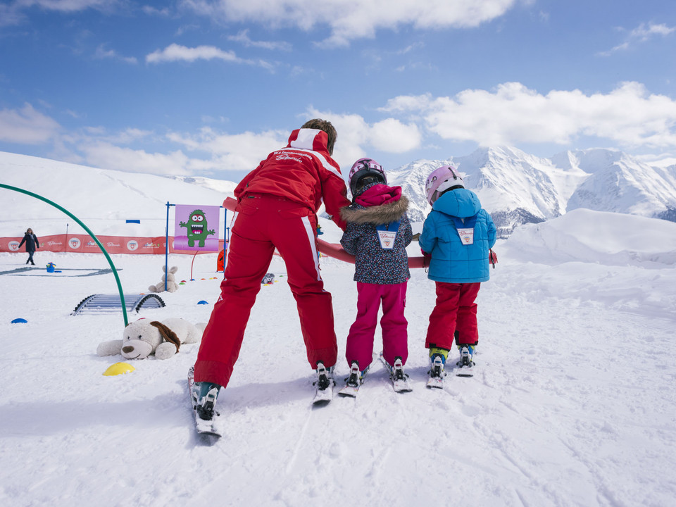 Cours de ski pour enfants au paradis de la neige de Bettmeralp Ski Schnupperkurs Bettmeralp mit Skilehrerin und zwei Kindern beim Skifahren lernen im KinderlandBettmeralp ski taster course with ski instructor and two children learning to ski in KinderlandCours d'initiation au ski Bettmeralp avec monitrice de ski et deux enfants apprenant à skier au Kinderland