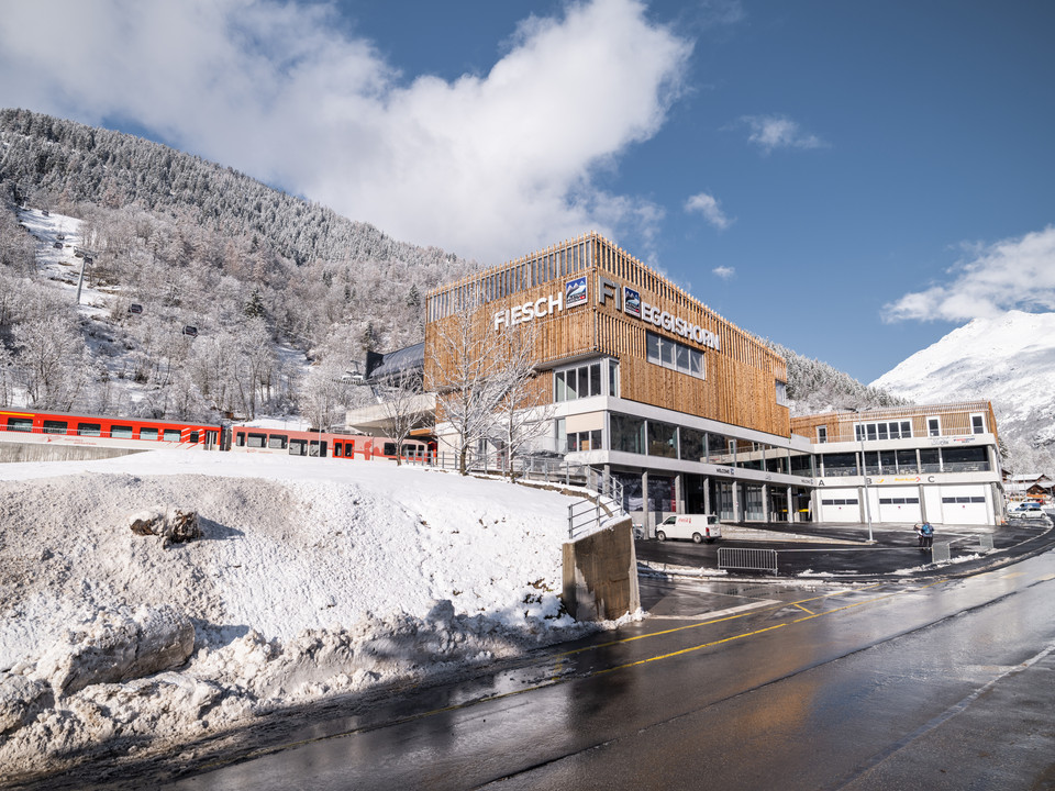 Hub hivernal des transports publics à Fiesch Bei der Mehrfahrt Aletsch Arena beginnt das Wintererlebnis am verschneiten ÖV-Hub Fiesch mit direkter Verbindung zu Zug und GondelbahnOn the Aletsch Arena multi-ride, the winter experience begins at the snow-covered Fiesch public transport hub with a direct connection to the train and gondola liftAvec le trajet multiple Aletsch Arena, l'expérience hivernale commence à la plateforme enneigée des transports publics de Fiesch, avec une liaison directe vers le train et la télécabine.