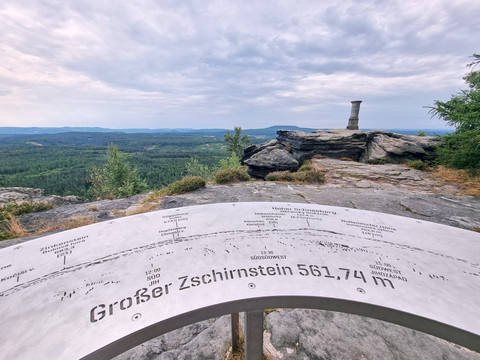 Aussichtspunkt mit Infoplatte und Inschrift "Großer Zschirnstein 561,7 m", Blick auf Landschaft und Steinmonument.