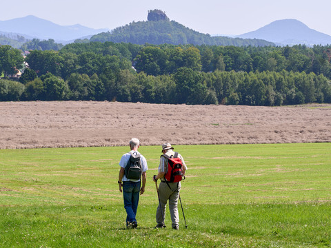 Blick vom Wolfsberg Zwei Wanderer auf einer Wiese mit Zirkelstein im Hintergrund.
