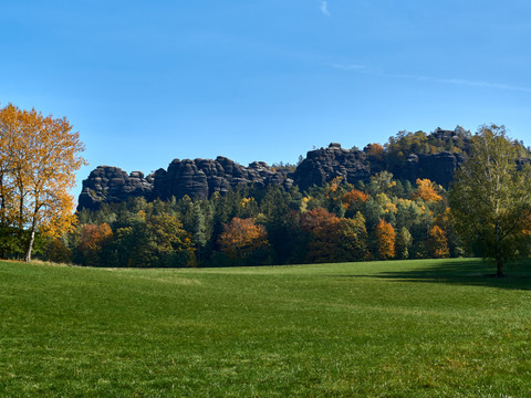 Pfaffenstein Herbstliche Bäume und Pfaffenstein unter blauem Himmel.