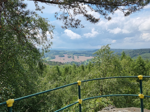 Hartenstein Aussichtspunkt mit Geländer überblickt grüne Landschaft und Gebäude in der Ferne.