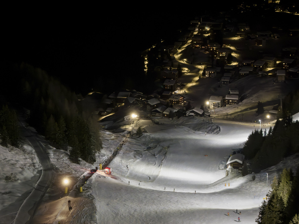 Beleuchtete Abfahrt oberhalb der Riederalp bei Nacht Beim Nachtskifahren Bettmeralp Riederalp leuchten die Skipisten oberhalb des Dorfes hell auf und bilden einen faszinierenden Kontrast zur dunklen BerglandschaftWhen skiing at night in Bettmeralp Riederalp, the ski slopes above the village light up brightly and form a fascinating contrast to the dark mountain landscapeLors du ski nocturne Bettmeralp Riederalp, les pistes de ski au-dessus du village s'illuminent et forment un contraste fascinant avec le paysage montagneux sombre.