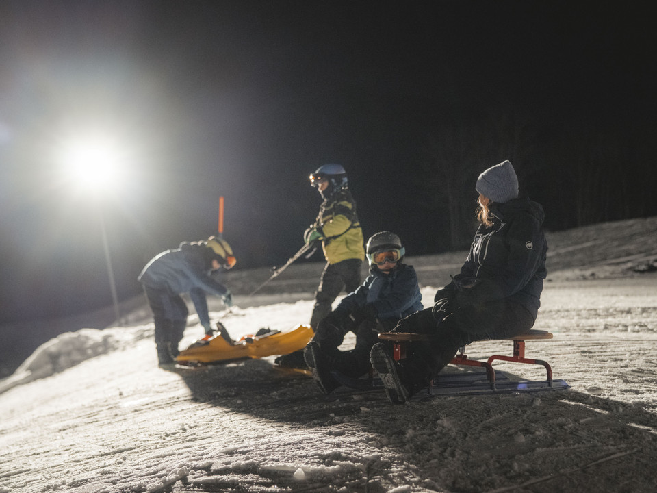 Familienabenteuer beim Nachtskifahren im Fieschertal Das Nachtskifahren Fieschertal zeigt eine Familie mit Schlitten unter Flutlicht beim nächtlichen Winterspass in der Aletsch ArenaNight skiing Fieschertal shows a family with sledges under floodlights during night-time winter fun in the Aletsch ArenaLe ski nocturne de Fieschertal montre une famille avec une luge sous les projecteurs lors des plaisirs nocturnes de l'hiver dans l'Aletsch Arena.