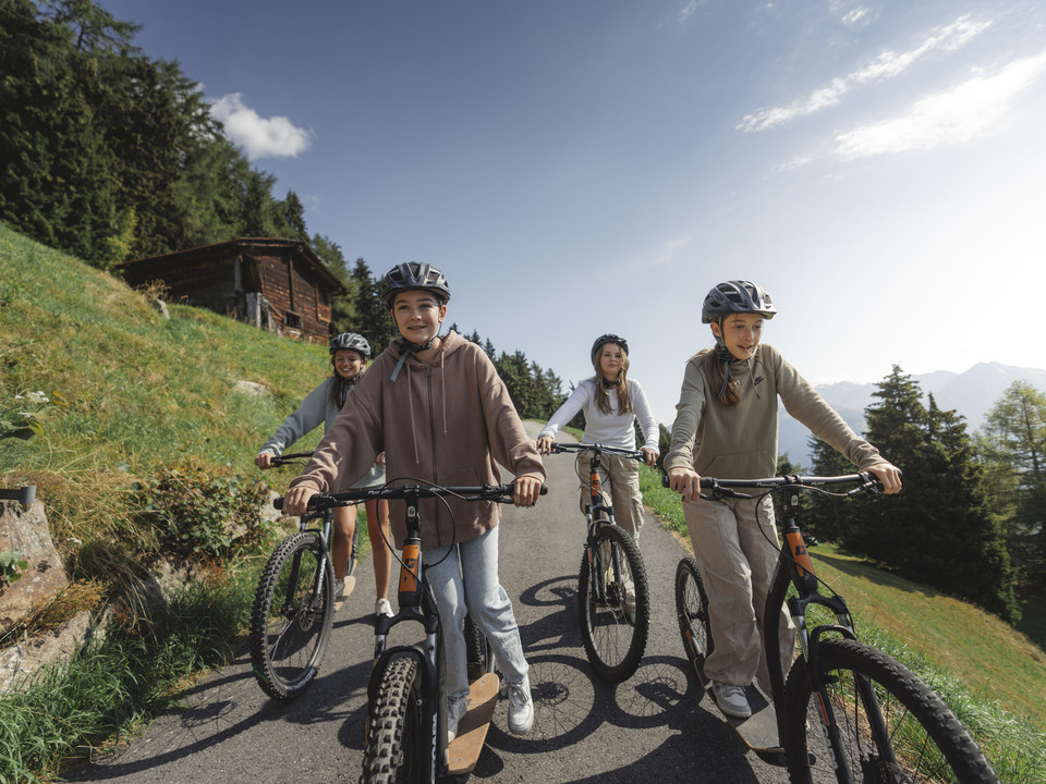 Freunde geniessen Trottinettfahrt in der Aletsch Arena Beim Trottinett Aletsch Arena fahren junge Freunde gemeinsam auf sonnigen Wegen unterhalb der Bettmeralp und geniessen den Blick auf die BergeOn the Aletsch Arena scooter, young friends ride together on sunny paths below Bettmeralp and enjoy the view of the mountainsLa trottinette Aletsch Arena permet à de jeunes amis de rouler ensemble sur des chemins ensoleillés en contrebas de Bettmeralp et d'admirer la vue sur les montagnes.