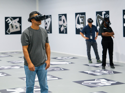 Drei Personen stehen mit VR-Brillen in einem großen Raum und beobachten eine VR-Experience bei der Ausstellung "Titanic: Eine Immersive Reise"Three people wearing VR goggles stand in a large room and observe a VR experience at the exhibition "Titanic: An Immersive Voyage"Tři lidé s brýlemi VR stojí ve velké místnosti a sledují zážitek VR na výstavě "Titanic: An Immersive Voyage".Trzy osoby noszące gogle VR stoją w dużym pomieszczeniu i oglądają doświadczenie VR na wystawie "Titanic: An Immersive Voyage".Drie mensen met een VR-bril staan in een grote ruimte en bekijken een VR-ervaring op de tentoonstelling "Titanic: An Immersive Voyage".Tre persone che indossano occhiali VR si trovano in una grande stanza e guardano un'esperienza VR alla mostra "Titanic: An Immersive Voyage".