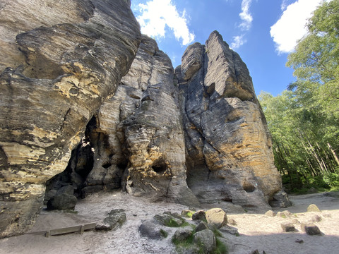 Sandsteinfelsen mit Höhlen und Bäumen unter blauem Himmel.