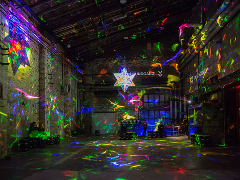 Farbenfrohe Lichtinstallation in einem industriellen Raum mit hohen Decken und Betonwänden.Colorful light installation in an industrial space with high ceilings and concrete walls.Barevná světelná instalace v industriálním prostoru s vysokými stropy a betonovými stěnami.Kolorowa instalacja świetlna w industrialnej przestrzeni z wysokimi sufitami i betonowymi ścianami.Kleurrijke lichtinstallatie in een industriële ruimte met hoge plafonds en betonnen muren.Installazione luminosa colorata in uno spazio industriale con soffitti alti e pareti in cemento.