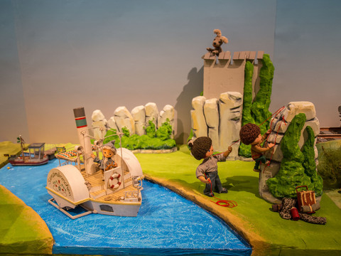 6 - Sandmännchen in Leipzig - Foto Andreas Schmidt.jpg Sandmännchen-Figur vor Flusskulisse mit Spielzeugboot und Puppen in einer Landschaftsszenerie.Sandman figure in front of a river backdrop with toy boat and dolls in a landscape scene.Postavička písečného muže na pozadí řeky s lodičkou a panenkami v krajinné scéně.Postać Sandmana na tle rzeki z zabawkową łódką i lalkami w krajobrazie.Sandmanfiguur voor een achtergrond van een rivier met speelgoedboot en poppen in een landschapsscène.Figura di Sandman davanti a uno sfondo fluviale con barca giocattolo e bambole in una scena di paesaggio.