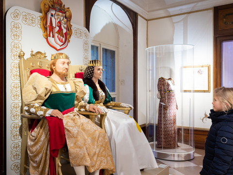 Wachsfiguren eines königlichen Paares in historischer Kleidung, beobachtet von Kind.