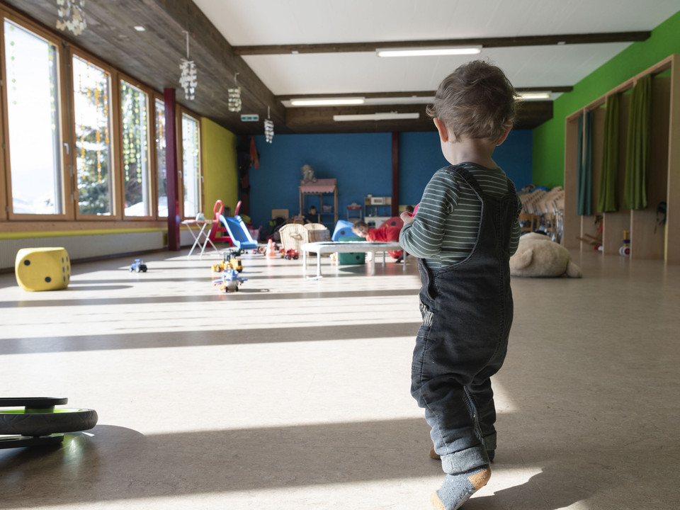 Entdecken und Bewegen Kleinkind bewegt sich selbstständig im Kinderhort Bettmeralp durch den hellen SpielraumToddler moves independently through the bright playroom in the Bettmeralp day nurseryUn petit enfant se déplace de manière autonome dans la salle de jeux lumineuse de la crèche Bettmeralp.