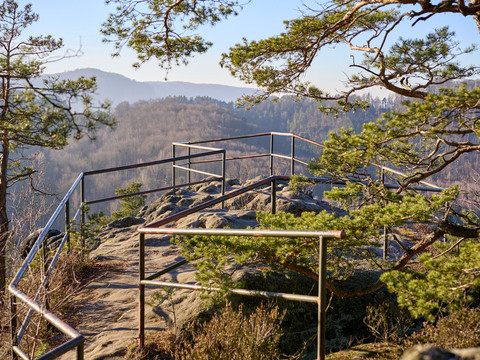 Geländer am Aussichtspunkt Großes Pohlshorn Aussichtspunkt mit Geländer auf einem Felsen, umgeben von Bäumen, Blick auf Berge.