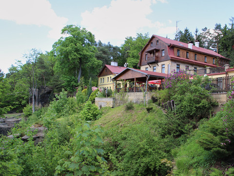 Belvedere Hrensko Gasthaus Haus mit rotem Dach auf grünem bewaldeten Hügel neben einem Fluss.