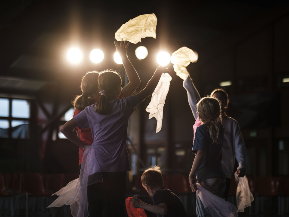 Ambiance lumineuse dans le manège Eine Kindergruppe hebt im stimmungsvollen Gegenlicht Tücher in die Höhe beim Mitmachzirkus Aletsch Arena.A group of children lift scarves into the air in the atmospheric backlight at the Aletsch Arena hands-on circus.Un groupe d'enfants soulève des draps dans un contre-jour évocateur au cirque participatif Aletsch Arena.