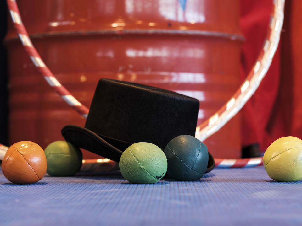 Les accessoires de cirque en détail Detailaufnahme im Mitmachzirkus Aletsch Arena mit einem schwarzen Zylinder und bunten Jonglierbällen auf einer Matte.Close-up in the Aletsch Arena hands-on circus with a black top hat and colorful juggling balls on a mat.Photo de détail au cirque participatif Aletsch Arena avec un cylindre noir et des balles de jonglage colorées sur un tapis.