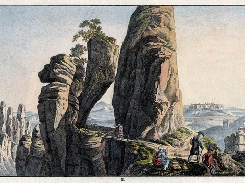 im Vordergrund Menschen links das Neurathener Felsentor und im Hintergrund das Elbsandsteingebirge mit Felsen und Tafelbergen