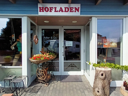Herzensgut_Hofladen_Üfingen_HD_16zu9.jpg Eingangsbereich des Hofladens Herzensgut mit dekoriertem Vorplatz und großen Schaufenstern.