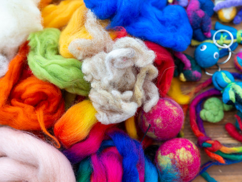bunte Ostereier Bunte Wolle und gefilzte Objekte in verschiedenen Farben, darunter Kugeln und Schlüsselanhänger.