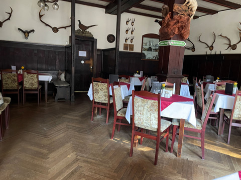 Zadní jídelna restaurace s prostřenými stoly a mnoha židlemi.