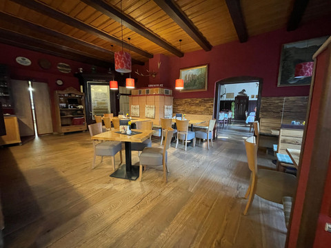 Přední jídelna s rustikálními dřevěnými stoly a krbem.