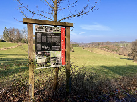 Bergischer Fuhrmannsweg Informationstafel des Bergischen Fuhrmannswegs entlang eines Wanderpfades in grüner Landschaft unter blauem Himmel.