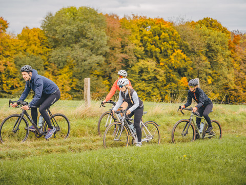 Radtour im Bergischen Vier Radfahrer:innen auf einer Tour im Bergischen Land im Herbst, entlang eines Feldes mit Bäumen.