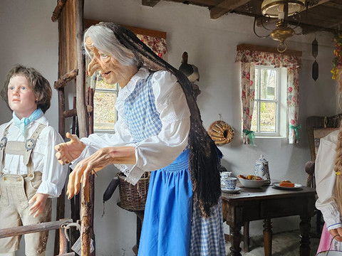 Hänsel und Gretel Figuren von Hänsel, Gretel und der Hexe in einer Hüttenszene mit rustikaler Einrichtung