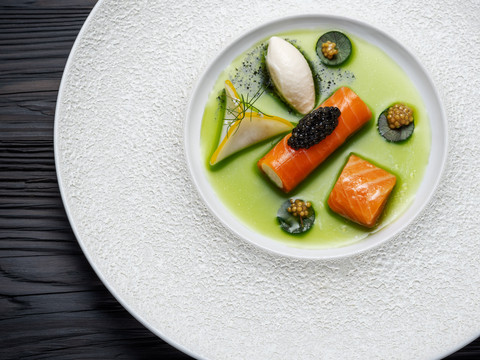 Gourmetrestaurant „Schote“ Fein arrangiertes Gourmetgericht mit Lachs, Kaviar und grüner Sauce auf weißem Teller