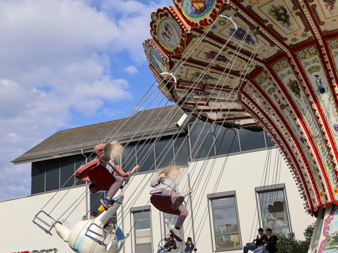 Waldbröler Stadtfest Kinder auf einem bunt verzierten Kettenkarussell vor modernen Gebäuden