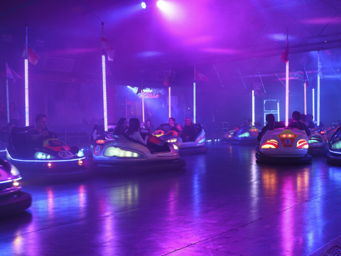 Waldbröler Stadtfest Neonbeleuchtete Autoscooter fahren in einer Halle mit buntem Licht und dichtem Nebel.