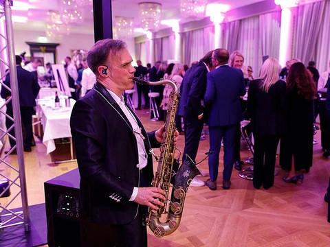 Falstaff Weintrophy Saxophonist spielt bei festlicher Veranstaltung in elegantem Saal.