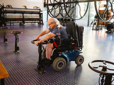 Rollstuhlfahrer beim Schwungraddrehen in der Fabrik der Fäden