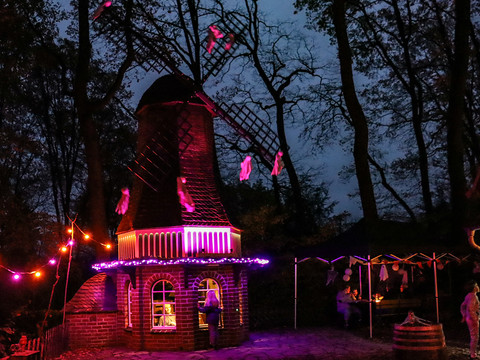 Gruseltage im Märchenwald Beleuchtete Windmühle im dunklen Märchenwald mit Geistern und bunten Lichtern