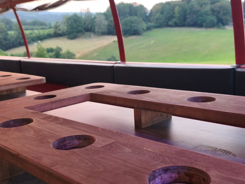 Wolle's Eventfahrten Holztische im überdachten Planwagen mit Blick auf grüne Felder und Wald.