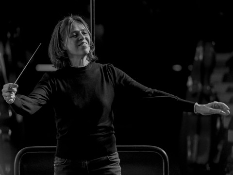 Silke Löhr Dirigentin Silke Löhr bei einem Konzert, mit Taktstock vor dunklem Hintergrund