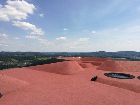 Aussichtsplattform mit Trampolinen auf :metabolon <p>Rosa-rotes Aussichtsdach mit sanften Erhebungen und weitem Blick auf Hügel und Himmel bei Lindlar.</p>